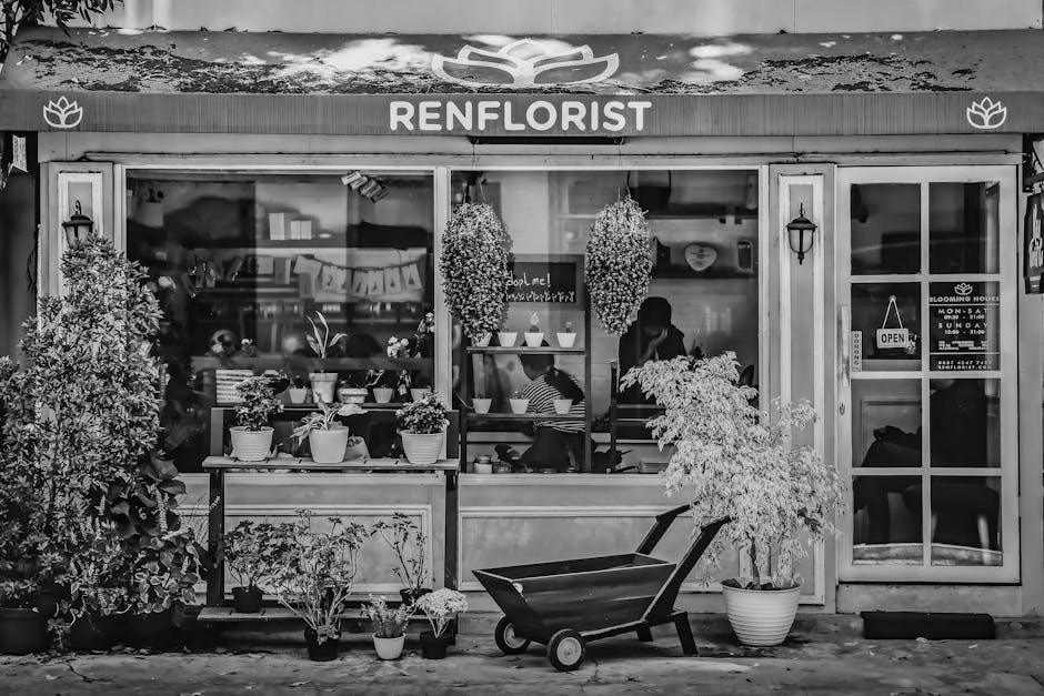 Black and white photograph of the exterior of Renflorist, a flower shop on Shepperton High Street near TW17, showcasing large glass windows displaying potted plants and floral arrangements inside. Out