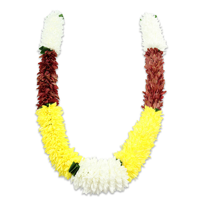 A meticulously made, U-shaped floral mala rests on a stark white background, the soft shadow beneath it emphasizing the garland's sculptural curve. The composition opens at both upper ends with plush, cream-white clusters of chrysanthemum-like blooms; these densely packed sections have a pillowy texture that reads like small, hand-tufted pom-poms. Directly below each white crown, bands of deep maroon - leaning toward a reddish-brown terracotta - introduce a solemn, grounding colour that contrasts with the radiance below. The maroon shifts into an extended field of vibrant yellow, where numerous tiny fabric petals are arranged to create a full, generous arc that dominates the visual flow. Where the two yellow arms converge at the base, a substantial and lush cluster of white blooms forms a central focal point, providing a thoughtful punctuation to the palette. Discreet dark green leaf accents are inserted at several transition points, particularly between the bottom white and yellow segments, to mimic the effect of natural separators and to add depth. The artificial materials have been assembled with patient attention: the repetition of thousands of petals gives an illusion of living abundance while assuring durability for repeated ceremonial use. In South Asian ritual practice this style of garland is used for temple offerings, bridal welcomes, and festivals like Diwali and Holi; the choice of white, yellow and maroon reflects traditional meanings of purity, prosperity and devotion. I picture this garland being chosen by families in Shepperton for home puja ceremonies or delivered to local community events along the High Street, where it would hang as an emblem of respect and celebration.