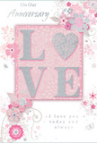 In this anniversary card, enduring romance is expressed through a palette of soft pastel pinks and silvery greys, very much in tune with the tranquil charm of Shepperton's riverside. The central focus is the word LOVE, crafted in raised, shimmering letters that form a tactile focal point. Each letter is edged with a fine dusting of glitter, and the O is artfully replaced by a silver-textured heart, slightly deeper and more reflective than the rest, inviting the fingers to linger. Behind and around this motif, the background glows in gentle blush pink, with barely perceptible variations in tone that suggest depth, like layers of tissue paper around a bouquet. From the edges of the letters, a pattern of delicate blooms unfurls in all directions. The flowers are rendered in tender shades of blush and mauve, with some petals almost translucent, as though painted in watercolour. Soft, flowing lines define each bloom, while slender stems curl into swirls and arabesques that weave between the blossoms. Tiny accents-subtle butterflies, small petals in mid-fall, and graceful curls-add a sense of light movement, recalling the feel of a breezy English spring garden. Silvery highlights trace parts of the petals and leaves, echoing the sparkle of early morning light on the Thames. The text On Our Anniversary and I love you today and always appears in a refined, handwritten-style script, carefully balanced so as not to overpower the floral artwork. The result is a card that feels like a keepsake arrangement captured on paper, ideal for marking a shared journey of love in Shepperton, with sentiment as soft as a whisper yet deeply heartfelt.